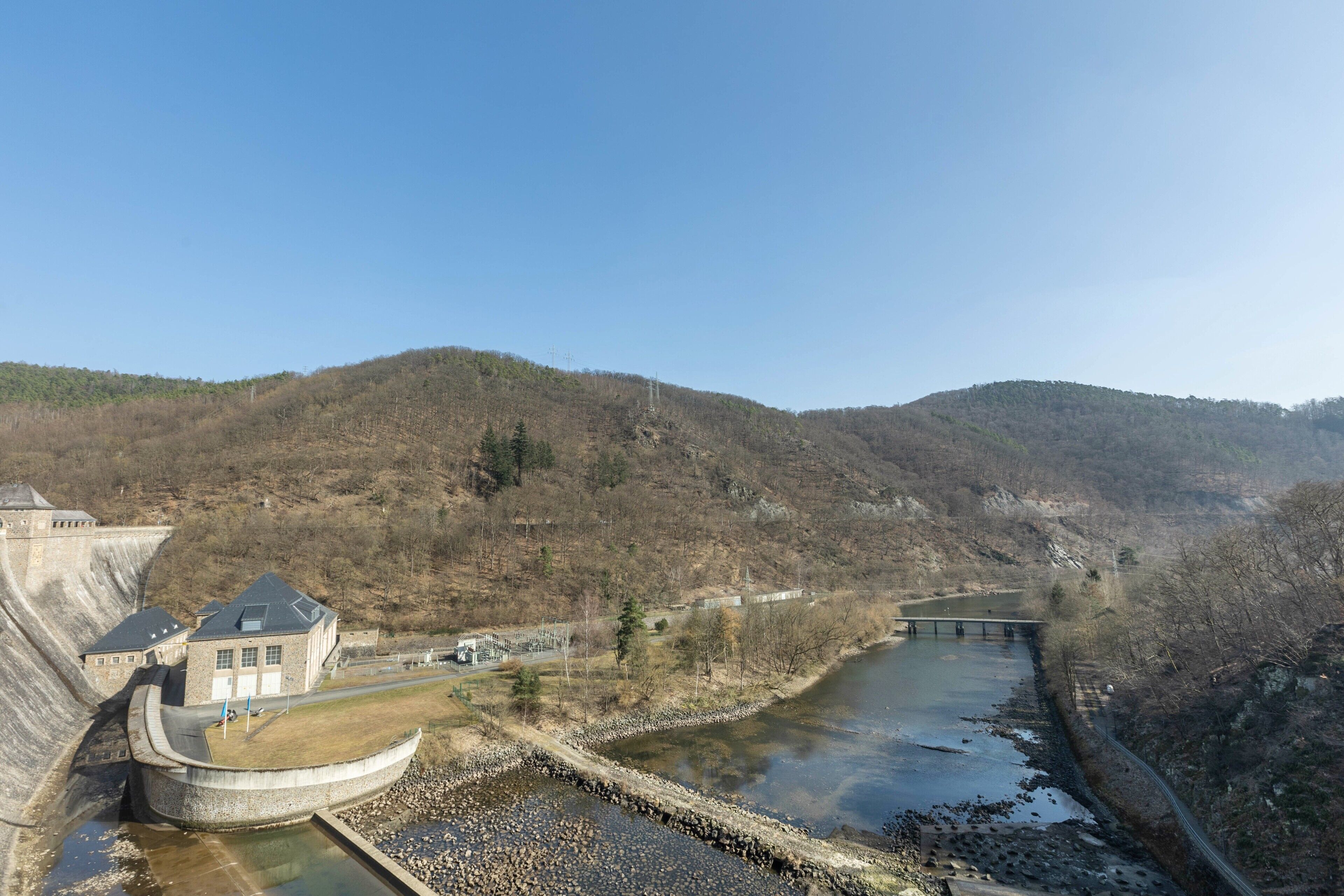 Una represa con un embalse, un edificio de techo inclinado y un paisaje montañoso.