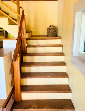 A wooden staircase with a handrail, leading to a landing with a wicker basket. - Marathon: Desert Oasis Retreat (Marathon)
