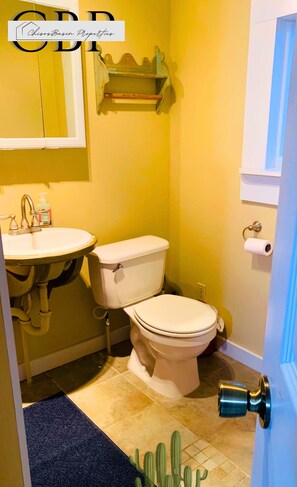 A compact bathroom with a sink, toilet, and a door with a blue handle. - Marathon: Desert Oasis Retreat (Marathon)