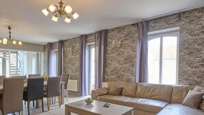 En moderne stue med en stenvæg, en beige sofa, et træbord og en lysekrone.