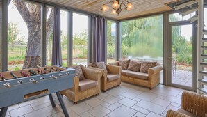 Una stanza ampia con soffitto in legno, ampie finestre e un tavolo da calcio da tavolo.