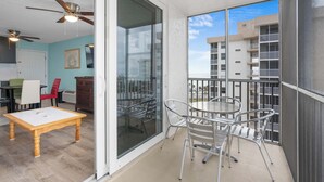A balcony with a table and chairs, a ceiling fan, and a view of the cityscape.