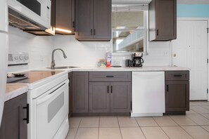 Eine moderne Küche mit dunkelbraunen Schränken, einem weißen Geschirrspüler und einem eingebauten Backofen.