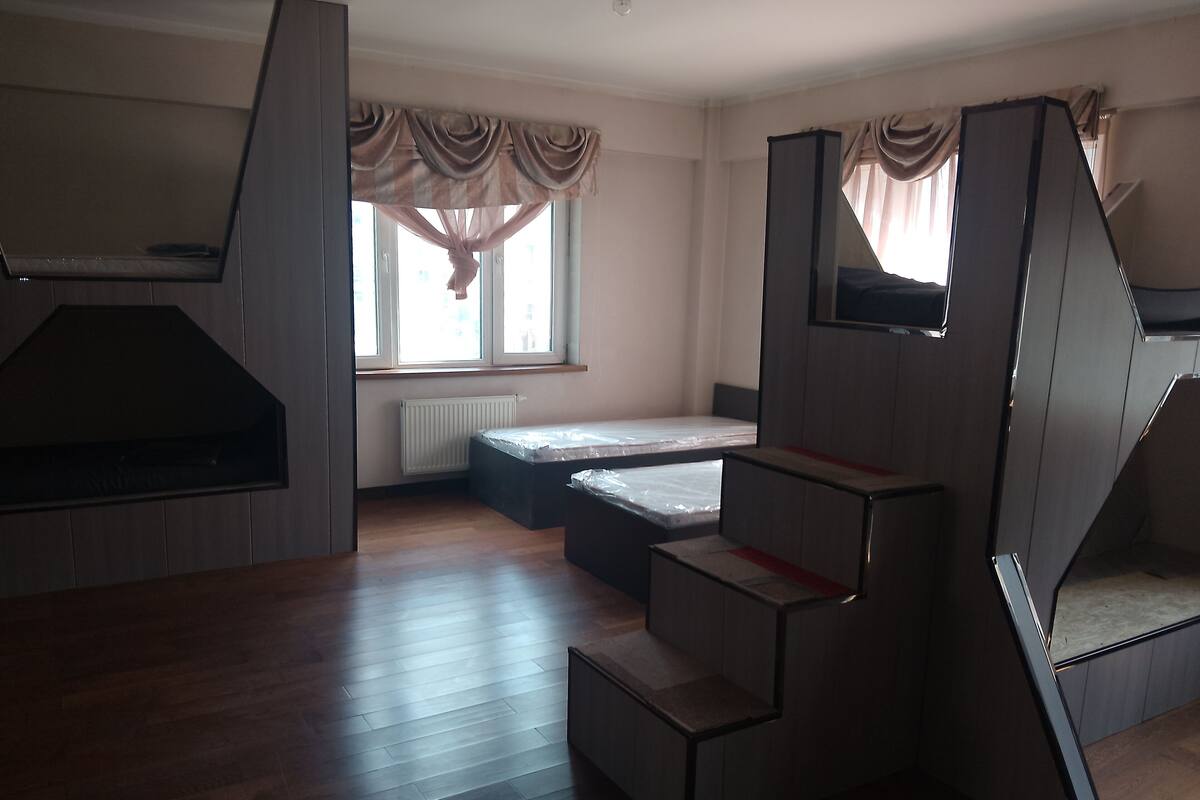 A compact room with a bed, a small seating area, and a kitchenette.