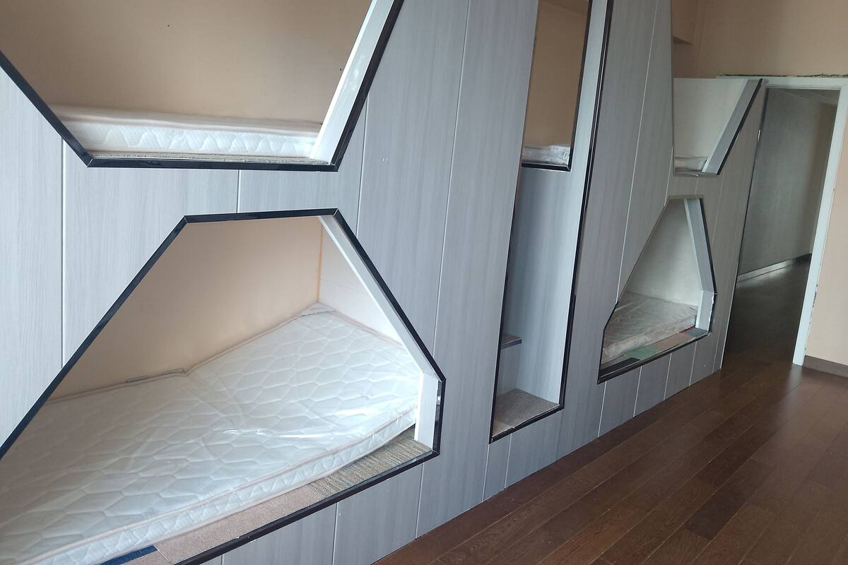 A room with a unique geometric design, featuring multiple hexagonal bunk beds with built-in storage compartments.