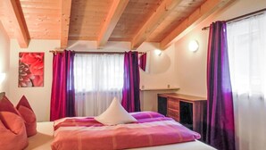 Ein Schlafzimmer mit Bett, Kissen, einem Schminktisch und Vorhängen.