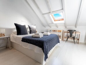Une chambre à coucher avec un lit, des oreillers, un bureau et une chaise.
