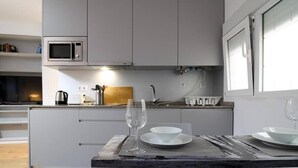 Eine moderne Küche mit integriertem Mikrowellenherd, einer Kaffeemaschine und einem Weinglas auf der Arbeitsplatte.