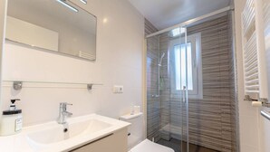 Ein modernes Badezimmer mit großem Spiegel, Waschbecken, Toilette und einer Duschkabine.