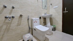 Un baño con inodoro, lavamanos, ducha y un pequeño taburete.
