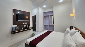 Habitación de hotel con cama, televisor montado en la pared, ventilador de techo y armario con espejo.