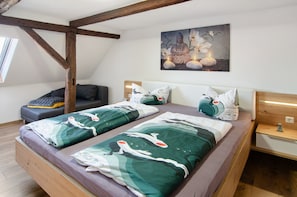 Une chambre avec deux lits, un plafond en bois, un tableau et une table de chevet.