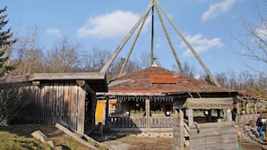 Een rustiek houten gebouw met een schuin dak, een houten hek en een bordje dat een restaurant aangeeft.