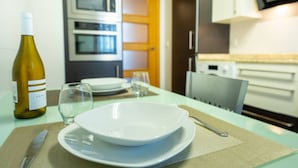 Eine Küche mit Esstisch für zwei Personen, einer Weinflasche und einer Mikrowelle.