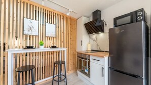 Eine moderne Küche mit einer Wand aus Holzlamellen, einem schwarzen Kühlschrank, einer Mikrowelle und einem Herd.