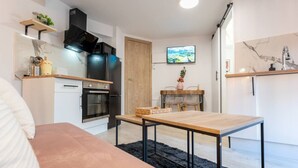 Eine moderne Küche mit Einbauofen, Mikrowelle und einer schwarzen Dunstabzugshaube. Es gibt einen Holzessttisch mit Stühlen und einen schwarzen Teppich auf dem Boden.
