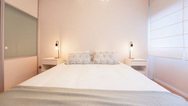 A bedroom with a large bed, two bedside tables, and a modern chandelier. - Fuentes de encanto en Santander 2 hab. (Santander)