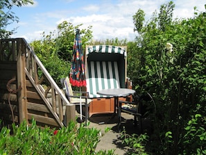Une terrasse en bois avec une chaise et une table, entourée de verdure.