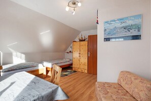 Une chambre avec deux lits, une armoire en bois, un canapé et un tableau au mur.