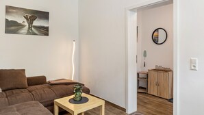 Un salon moderne avec un canapé d’angle, une petite table en bois et un tableau accroché au mur.