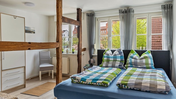 Une chambre avec un lit superposé, une chaise, un bureau et une fenêtre avec des rideaux.