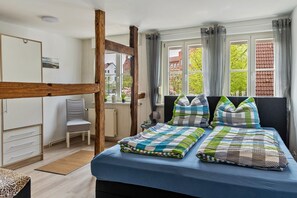 Une chambre avec un lit superposé, une chaise, un bureau et une fenêtre avec des rideaux.