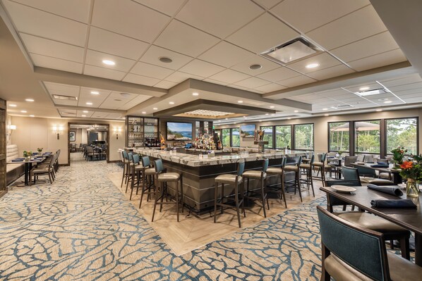 A spacious hotel lobby with a bar area, seating arrangements, and large windows offering views.