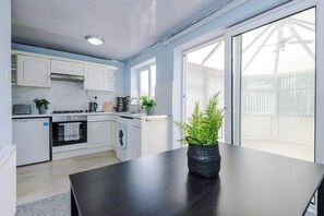 A modern kitchen with white cabinets, a dark countertop, and a potted plant.