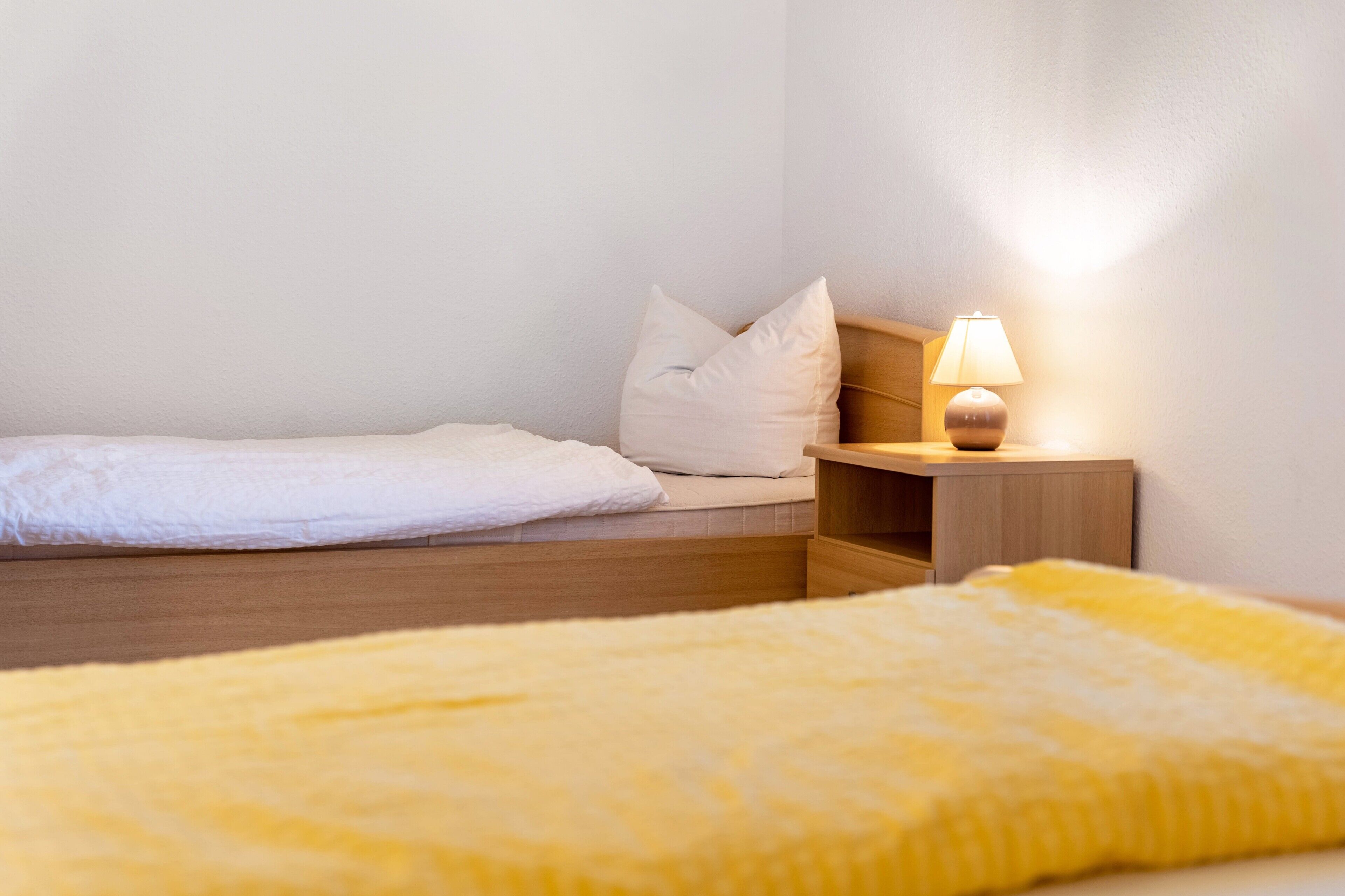 Ein Schlafzimmer mit einem Bett, einem Nachttisch mit Lampe und einem Holzkopfstück.