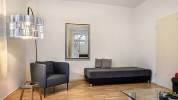 A modern bedroom with a bed, a chair, a glass table, and a floor lamp.