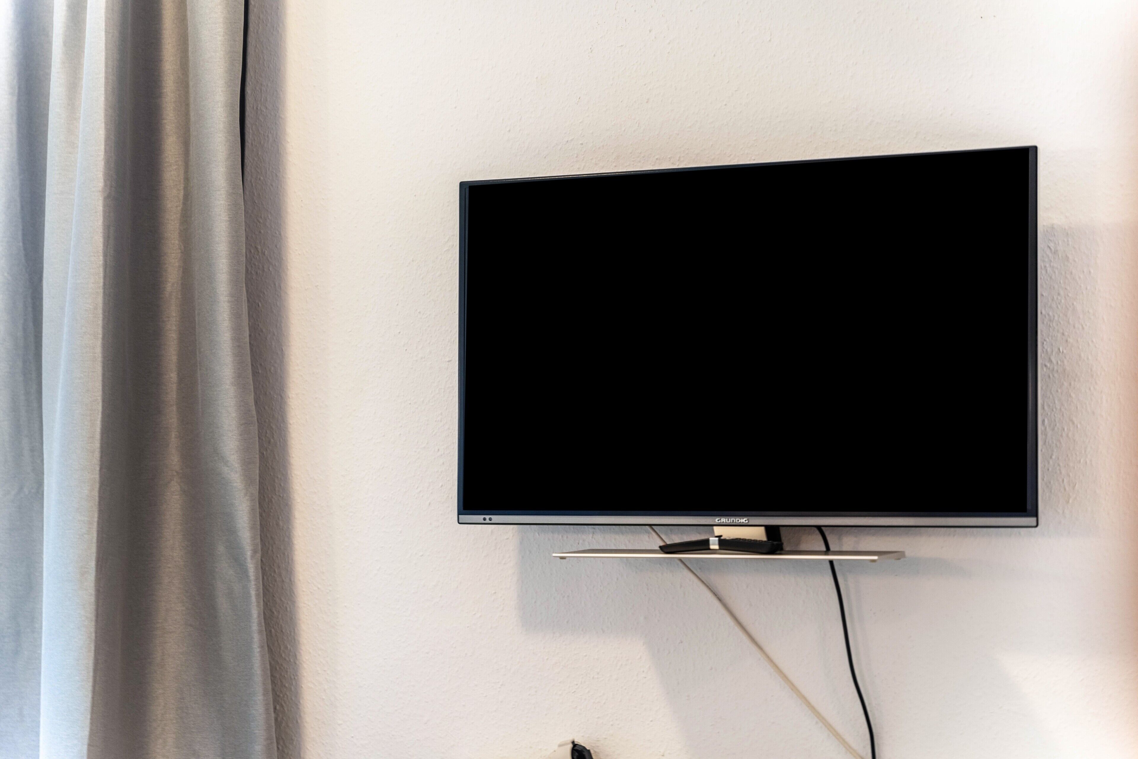 Ein Flachbildfernseher an der Wand befestigt, mit angeschlossenem Kabel.
