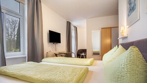A hotel room with two beds, a TV, a desk, and a chair.