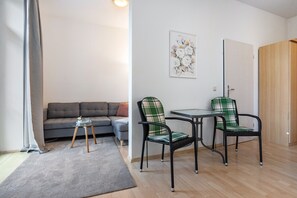 Ein modernes Wohnzimmer mit einer Couch, zwei Sessel, einem kleinen Tisch und einer Tür.