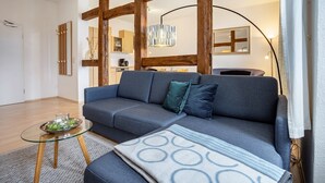 A modern living room with a sofa, a glass coffee table, and a patterned throw.