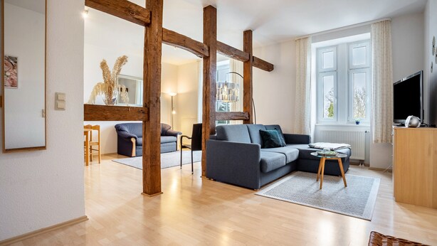 A modern living room with a sofa, a television, and a large window.