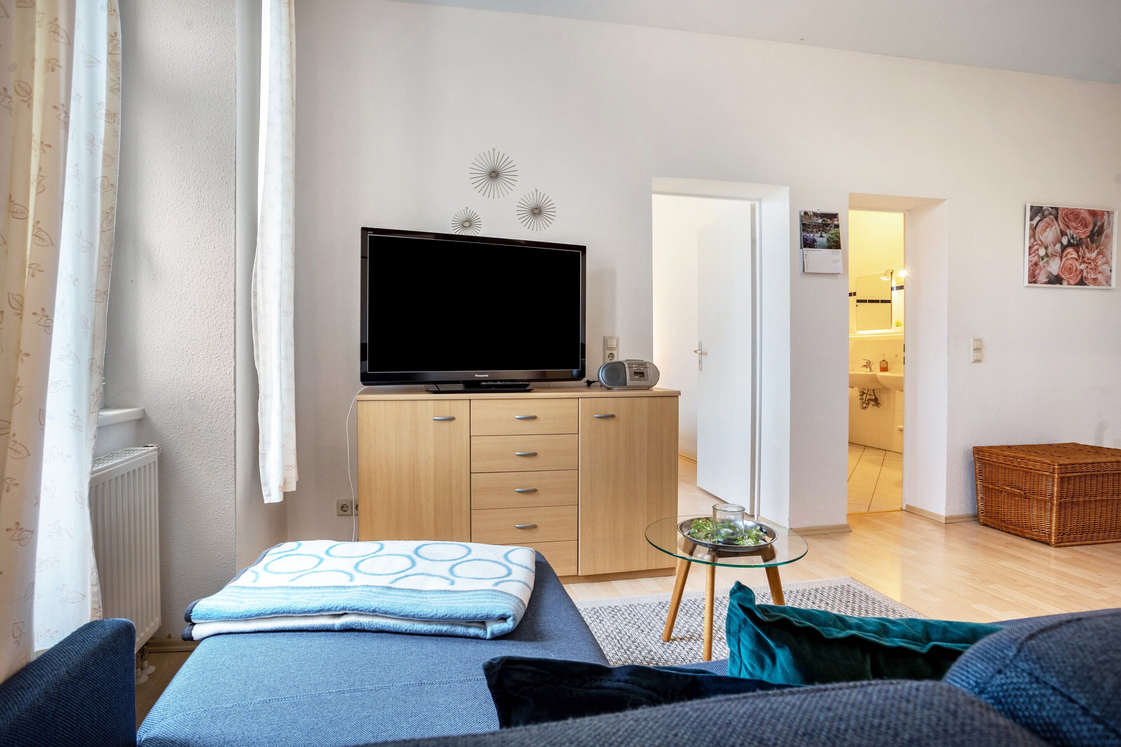 En moderne stue med fjernsyn, sofa og et lille bord med glasplade.