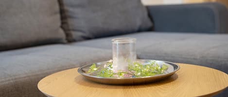 A round wooden table with a glass candle holder and a metal tray with flowers.