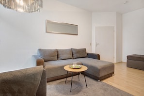 En moderne stue med sofa, rundt sofabord og en dør.