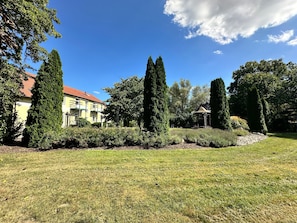 A residential area with a well-maintained lawn, a gazebo, and a building with a red roof.