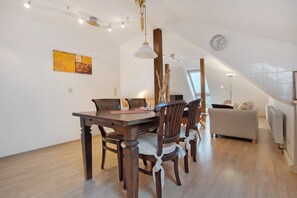Un coin repas avec une table et des chaises en bois, un luminaire suspendu et une horloge au mur.