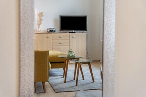 A room with a television on a wooden cabinet, a small table with a plant, and a yellow chair. - Apartment 'Landgräfin 12' with Shared Garden and Wi-Fi (Groß Plasten)