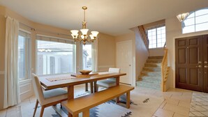 A dining area with a wooden table, bench, and chandelier. There is a staircase leading to a second floor. - Home on Golf Course w/ Private Pool in Phoenix! (Phoenix)