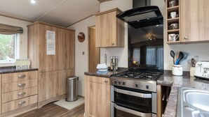 A modern kitchen with wooden cabinets, a gas stove, an oven, and a sink. - Cairn View by Interhome (Aviemore)