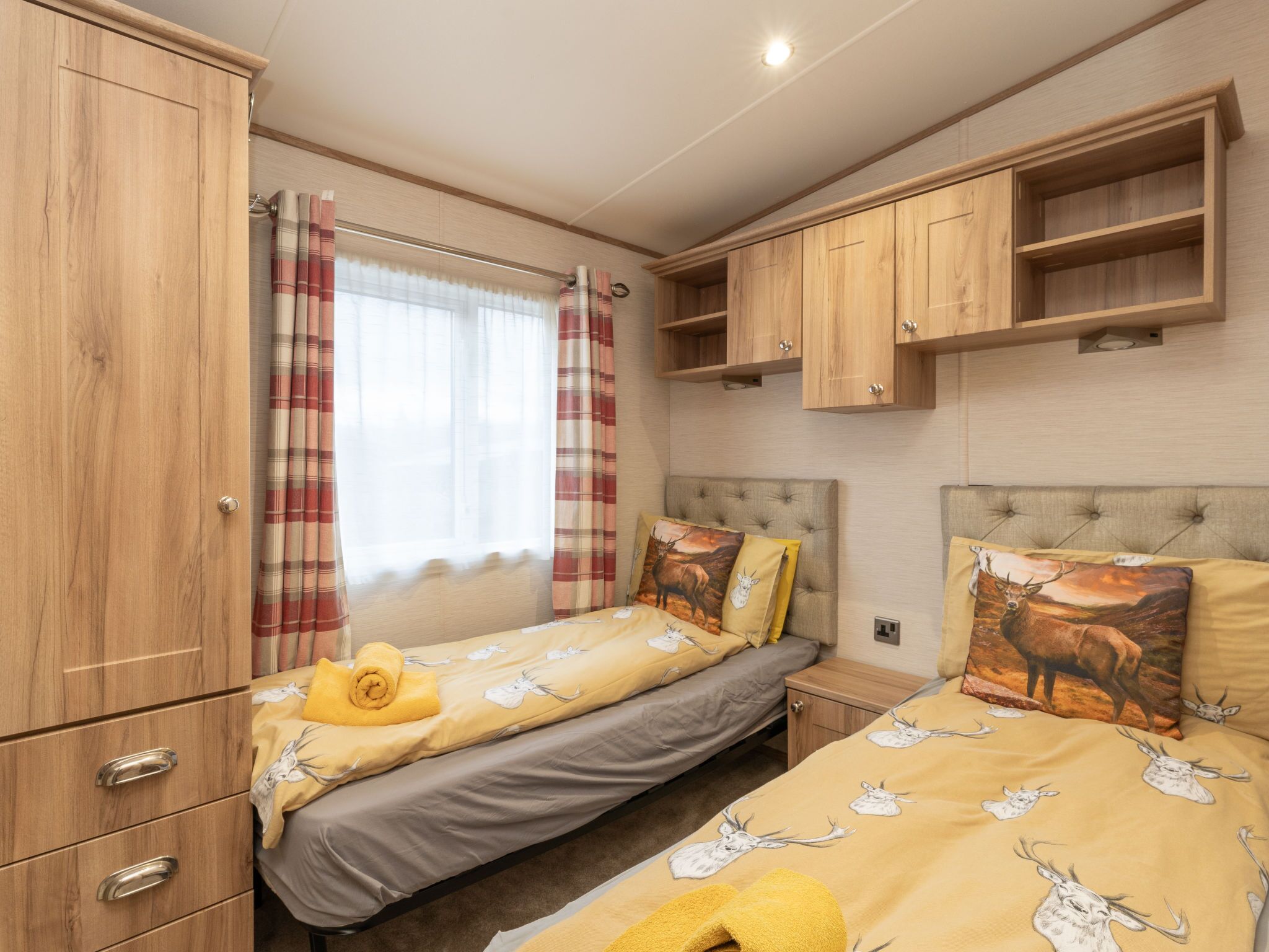 Een slaapkamer met twee bedden, houten kasten en een raam met gordijnen.