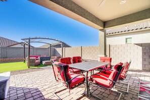 Relax in the serene patio area with a table and chairs, surrounded by a low brick wall and lush greenery.