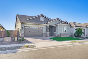 Two-story house with a garage door and well-maintained front yard, surrounded by a low fence.