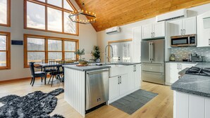 Een ruime keuken met houten balken, grote ramen en moderne apparatuur.