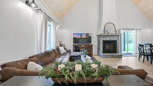 Amplia sala de estar con techo alto, chimenea, un sofá grande y una mesa de centro con un adorno.