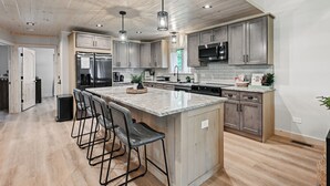 Una cocina moderna con armarios de madera, electrodomésticos de acero inoxidable y una isla central con taburetes de bar.