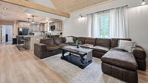 Un salón amplio con un sofá modular, una mesa de centro y una cocina al fondo.